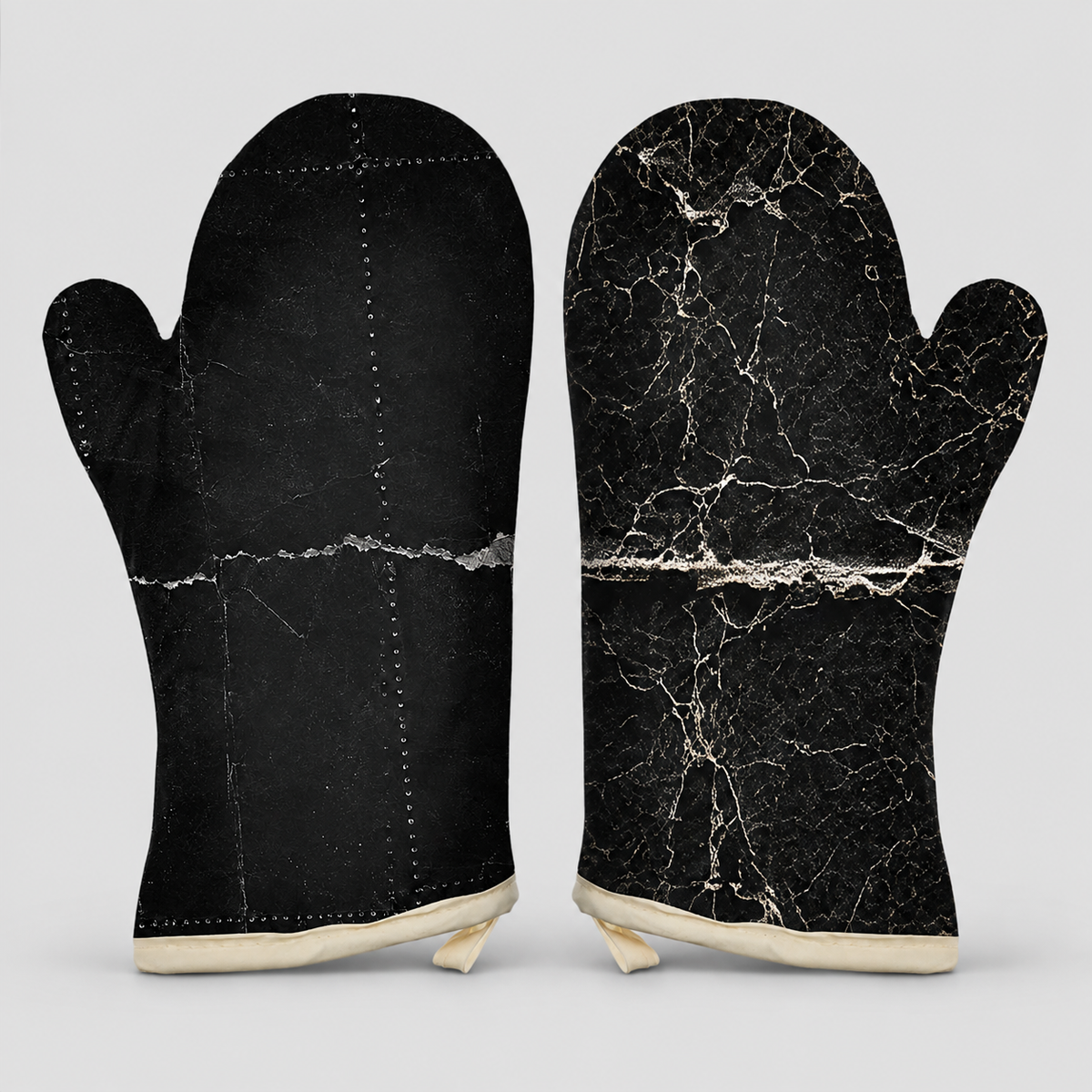 A pair of oven mitts shown front and back on a light gray background. The back side is solid black with visible stitching, and the front side features a black marble pattern with white veining.