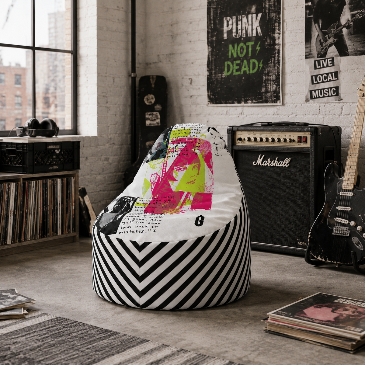 A bean bag chair featuring a white top half with a colorful graphic print of a woman and black-and-white chevron stripes on the bottom half, styled in a music-themed room with a Marshall amp, guitar, and vinyl records.