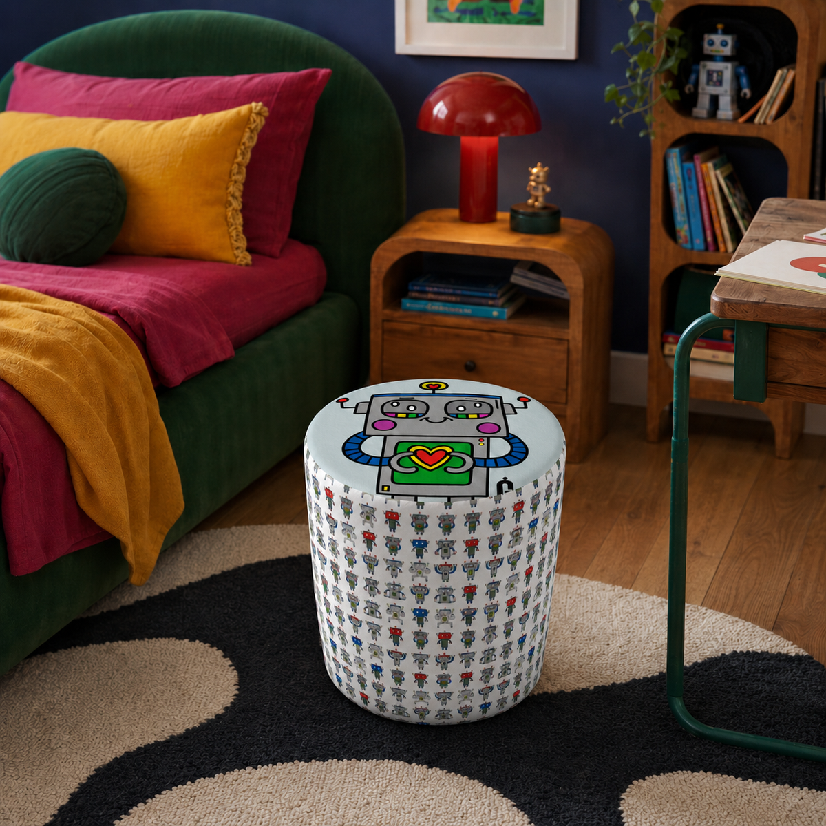 A cylindrical fabric-covered stool in a colorful children's bedroom, featuring a cartoon robot holding a green heart-shaped box on a white patterned base. The room includes a green bed, wooden furniture, and a dark blue wall.