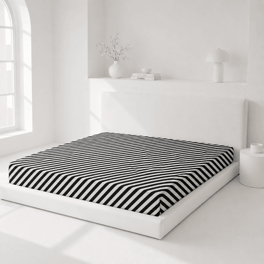 Bed with black and white striped mattress cover in a minimalistic room.